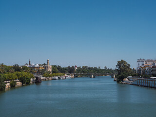 View of the city of Seville from the Guadalquivir river with the Torre del Oro (Tower of gold) and the north tower of the Plaza España (Spain Square) in the background