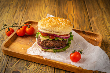 Homemade delicious hamburger on a wooden table, rustic style. Fast food. Space for the text.