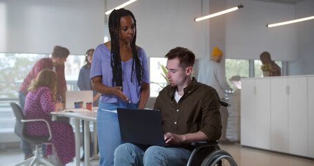 Young man in wheelchair working with female colleague