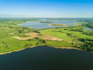 Beautiful aerial landscape on lake village with drone. Many lake islands covered with forests, fields on a sunny day