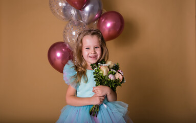 portrait of a little girl holding a bouquet of fresh flowers on a beige background with balloons