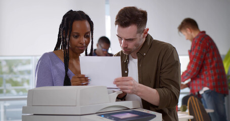 Two diverse office workers working in creative agency printing documents