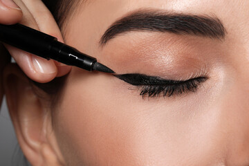 Artist applying black eyeliner onto woman's face, closeup