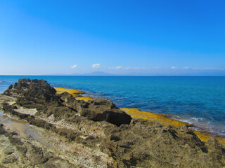 Fototapeta na wymiar Rocky shore of the Ionian Sea against the background of azure sea water