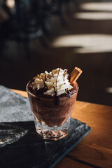 hot drinking chocolate in glass with whipped cream chocolate sauce and cinnamon stick