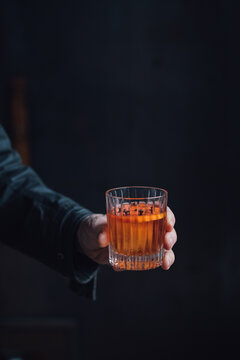 Hand Holding Whiskey Cocktail In Crystal Rocks Glass