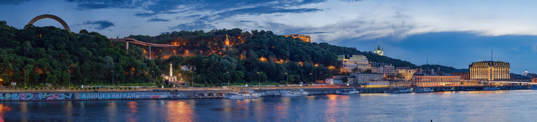 Obraz premium Night panorama of Kiev, where you can see the Dnieper River, the embankment, Pochtovaya Square, St. Andrew's Church, the People's Friendship Arch, Vladimirskaya Gorka.