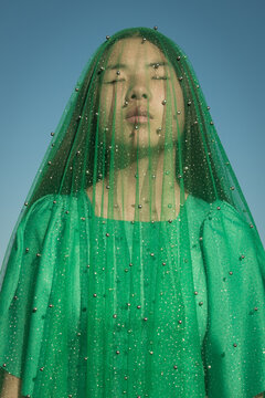 asian girl with green veil under blue sky like virgin mary statue 