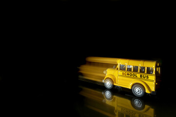 a single yellow school bus toy showing movement forwards shot against a black background