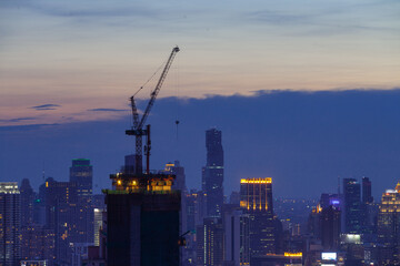 Fototapeta na wymiar hight crane work on hight building in the city on twilight sky sunset evening 