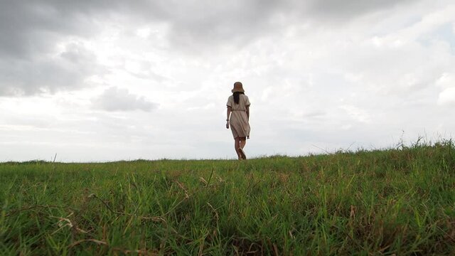 Young asian woman on a field with sunrise in the cloudy day 
