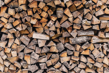 Background of stacked chopped wood logs. Wooden textured background. Harvesting firewood for the winter. A stack of firewood.