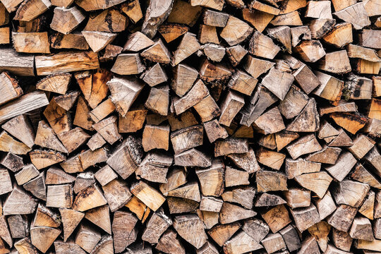 Background of stacked chopped wood logs. Harvesting firewood for the winter. A stack of firewood. Wooden textured background.