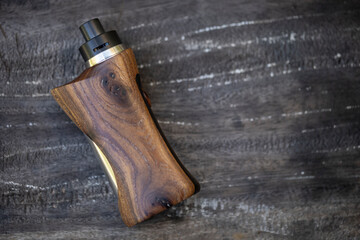 high end rebuildable dripping atomizer with stabilized natural walnut regulated box mods on dark...