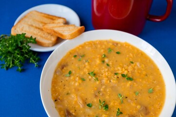 Creamy soup from orange lentil , herb, bread and pot.