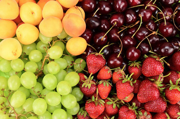 Fruits laid out on a horizontal surface. Apricots, grapes, strawberries and cherries