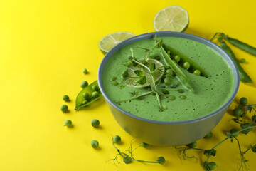 Plate of pea soup and ingredients on yellow background