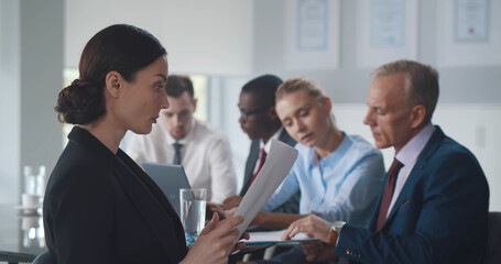 Young beautiful businesswoman reading contract at meeting in office