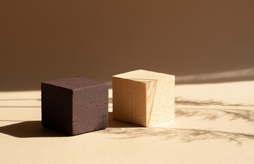 Two square stands in pastel colors for displaying products. Objects cast shadow on surface, from...