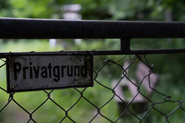 German sign on a fence saying private property - bench and grass in the background