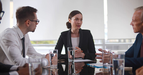 Group of businesspeople sitting in meeting room and listening to female speaker.