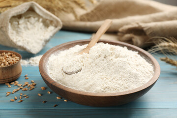 Wheat flour in bowl on light blue wooden table
