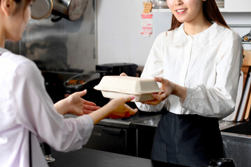 飲食店で働くエプロン姿の女性とお客のテイクアウトイメージ
