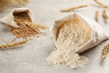 Sack of flour and wheat ears on light grey table