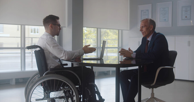 Disabled man at job interview in office talking to mature executive