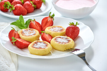 Cottage cheese pancakes, syrniki, ricotta fritters on ceramic plate with fresh strawberry.