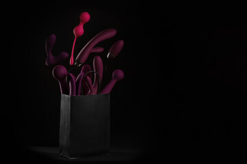 A paper shopping bag filled with Purple silicone sex toys on a black background. Erotic toy for...