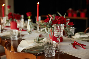 Unusual decoration of a wedding table with red roses, eucalyptus in red boxes with red candles and chili peppers in a dark interior