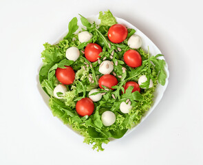 Top view salad with mozzarella cheese arugula, lettuce leaves, spinach, tomatoes and sunflower seeds