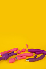 Erotic pleasure toys on a yellow background. Sex gadgets and masturbation devices. Rubber and silicone, pink and purple dildos, vibrators, butt plugs, vaginal balls and clitoral massager. Sex Shop.