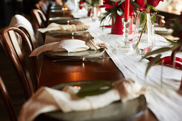 Unusual decoration of a wedding table with red roses, eucalyptus in red boxes with red candles and chili peppers in a dark interior