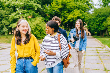 Obraz premium Group Photo. Portrait of cheerful multicultural students talking and walking outdoors at university campus, having fun meeting together in park.
