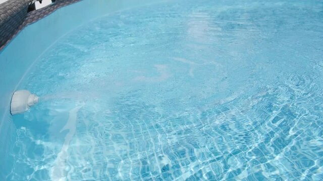 Teal color water in the above ground pool with light reflections. Recreation concept