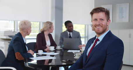 Handsome businessman at corporate meeting looking at camera and smiling