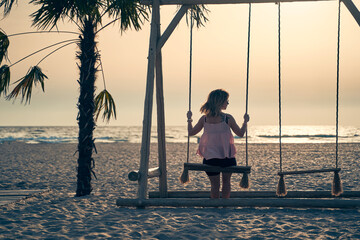 Young attractive woman is resting on seesaw on the beach at sunset.