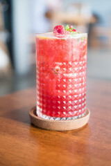 Black tea of lemon raspberry lemonade in glass on wooden table.