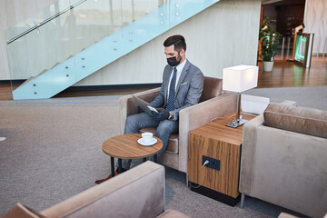 Serious businessman using two gadgets while working