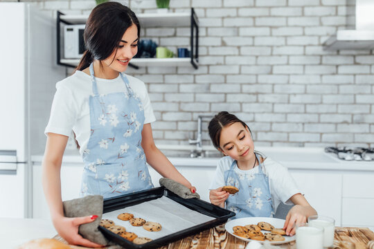 Mom and doughter cooking cookies together in modern white kitchen