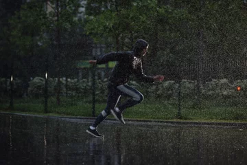 Fotobehang Man jogging under rain, flash light © antgor