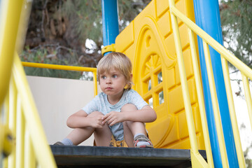 A bully child sits on a slide in the playground