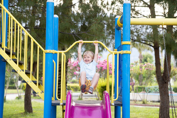 Happy child riding a slide in the playground against the beautiful nature background