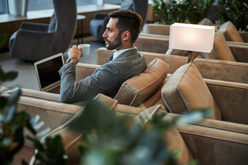 Serious handsome person drinking coffee in the business lounge