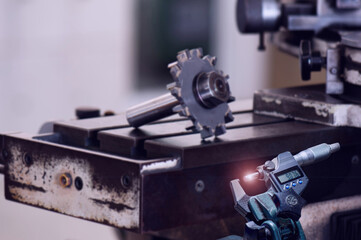 Fototapeta na wymiar digital hand holding micrometer 0-25 mm. in front cutter on machine tool grinding. Measuring engineer tool.