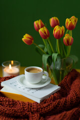 Espresso in white coffee cup with colorful tulips and candle. 