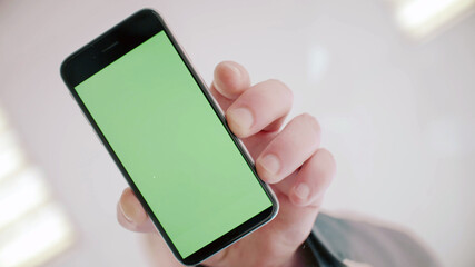 Businessman taking mobile phone with green screen from glass table