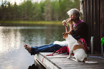 Woman with dog relaxing next to boat house